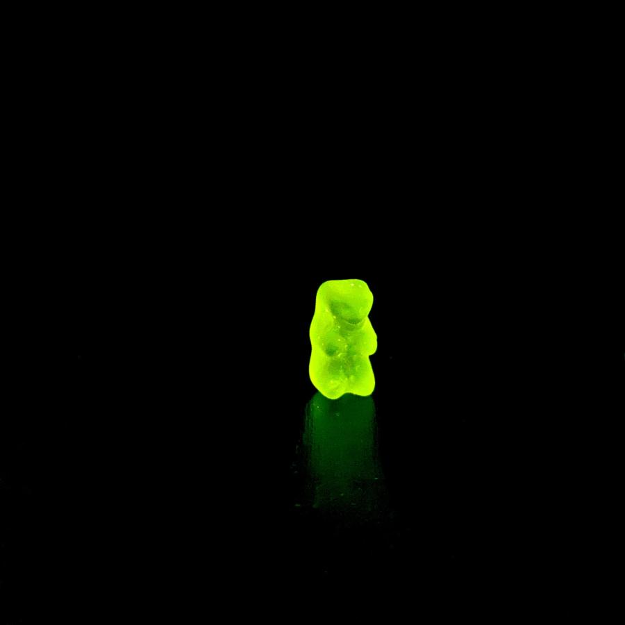 A lone yellow gummy bear sits in a black void. 