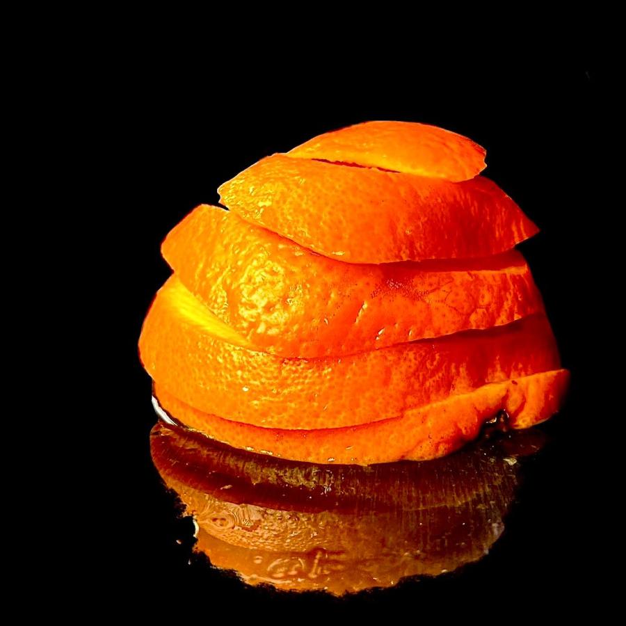 Orange peels arranged in a spiral sitting in a black void. 