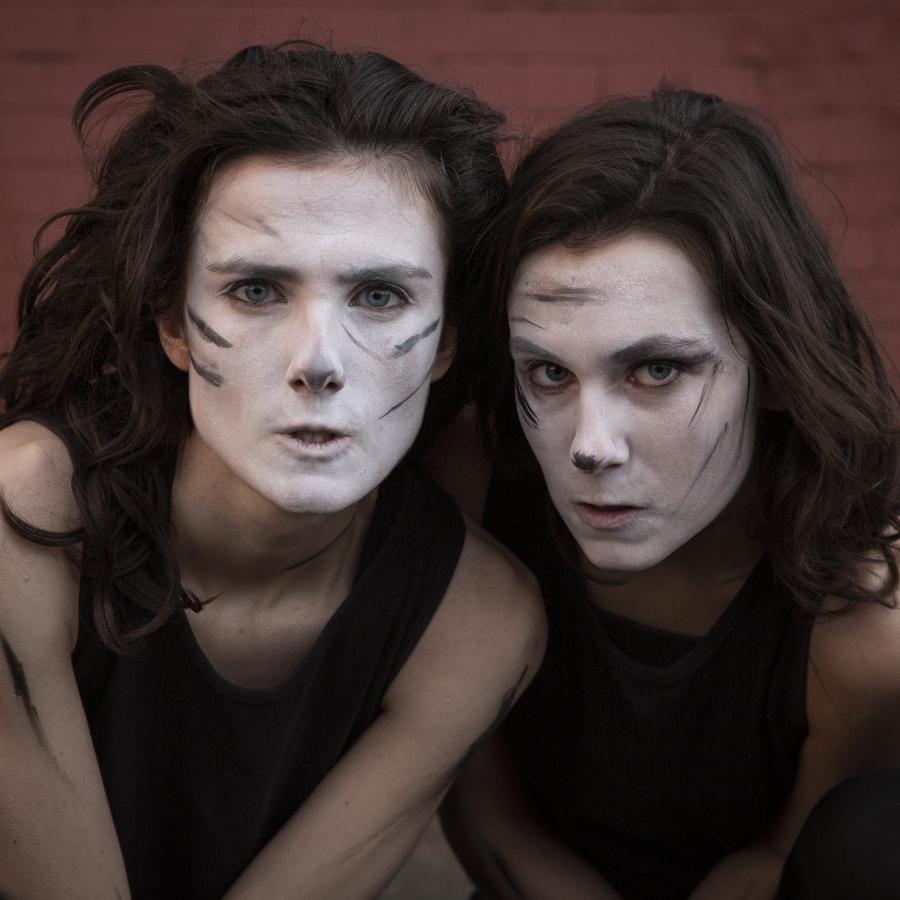 Two women looking at camera, faces smeared with white paint and black lines  