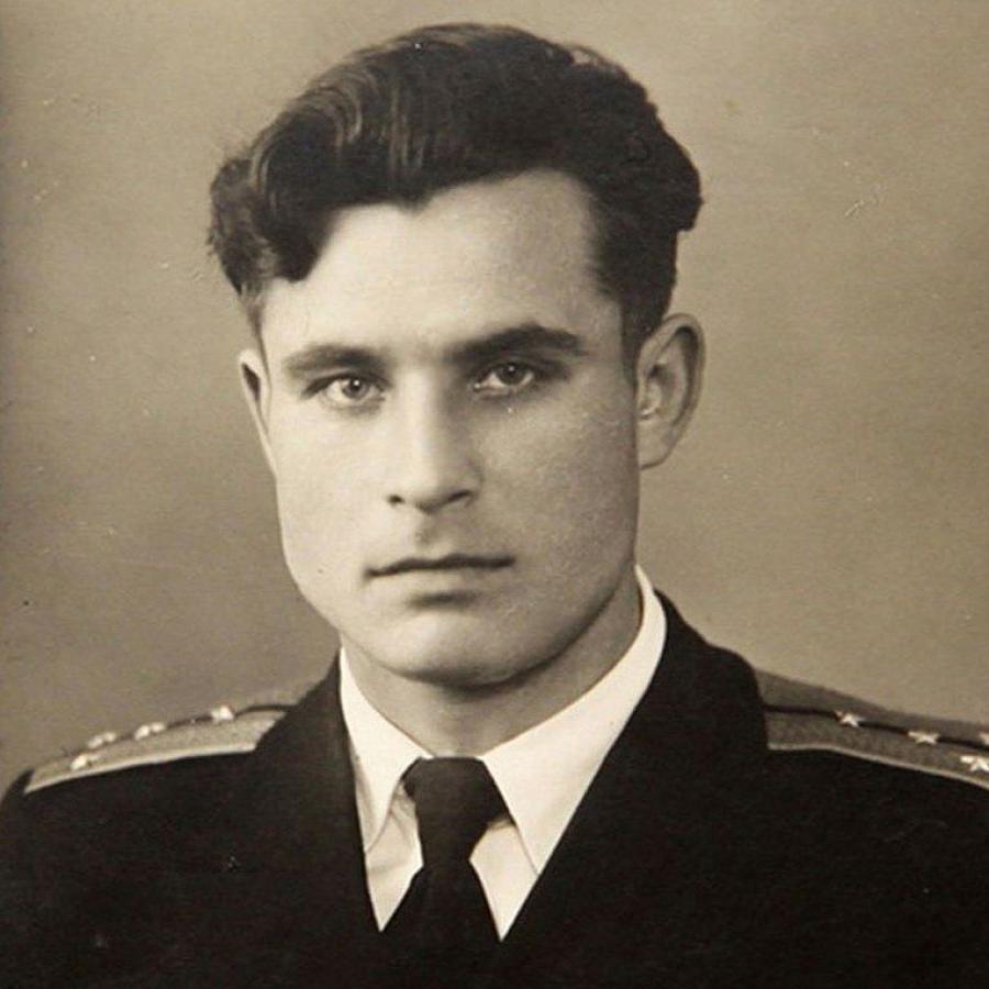 Portrait of Vasili Arkhipov wearing a dark Soviet naval uniform with medals, looking directly at the camera with a calm, serious expression against a plain background.   