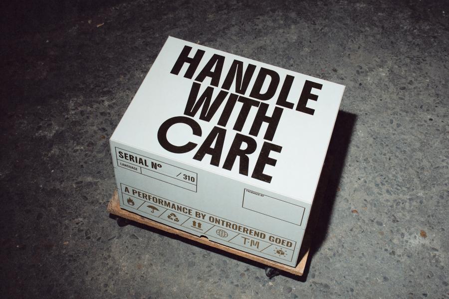 A photo of a cardboard box that says Handle With Care on it in thick black letters