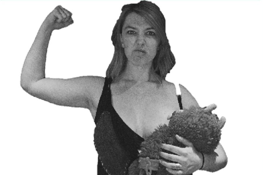 Heather, a white woman with a punk hairstyle and disgruntled face, holds one arm up displaying her muscles, the other holds a blue toy monster who she is breastfeeding. The image is black and white with a green banner above which reads 'Mummy Vs' - like a
