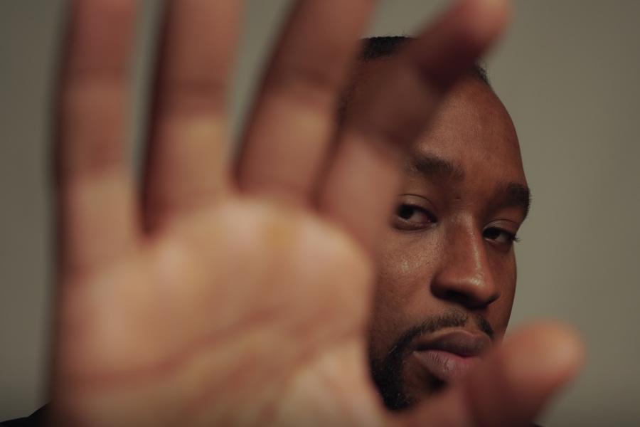 The palm of a man's hand close to the camera partially concealing his face