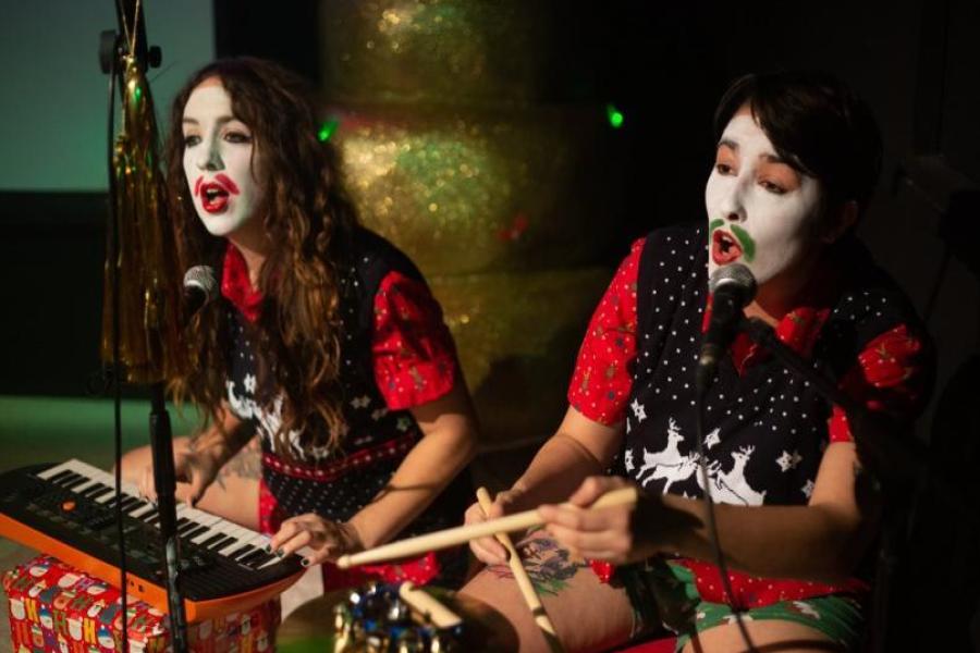 Two performers in a white facepaint with moustaches drawn on. 