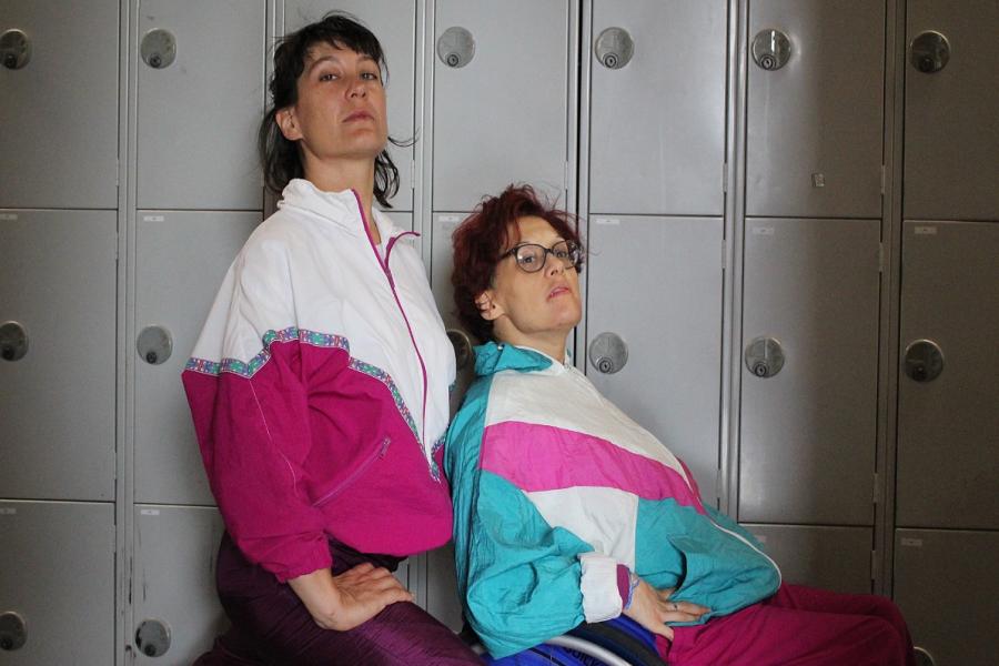 Performers, Kimberley Harvey and Anne-Gaëlle Thiriot are dressed in vintage late 1980's/early 1990's shell suits in shades of turquoise, white and fuchsia. Positioned side-on to the camera, hands on hips, looking over their shoulder towards the horizon.