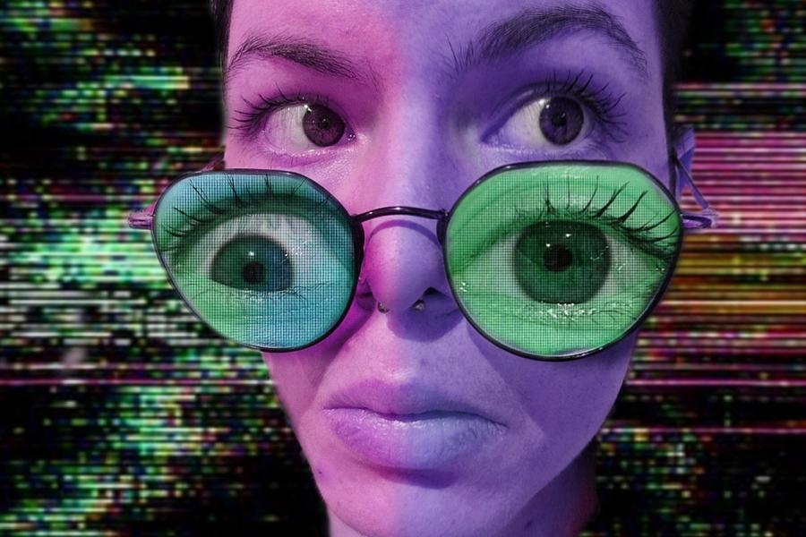 A pink and purple close-up of a person's face on a glitchy background. They look to the right with surprise/concern. They are wearing a pair of thin-framed glasses on the edge of their nose, which contains a green pair of eyes looking straight forward.