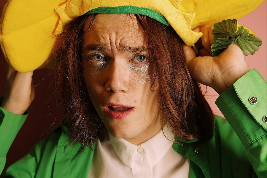 Somebody in a flower costume holding a yellow flower hat.