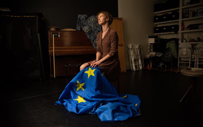 Anna kneeling on the floor holding an EU flag