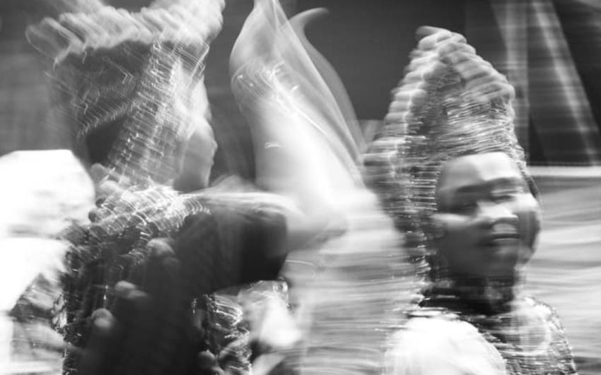A blurry black and white photograph of two Malay performers mid show