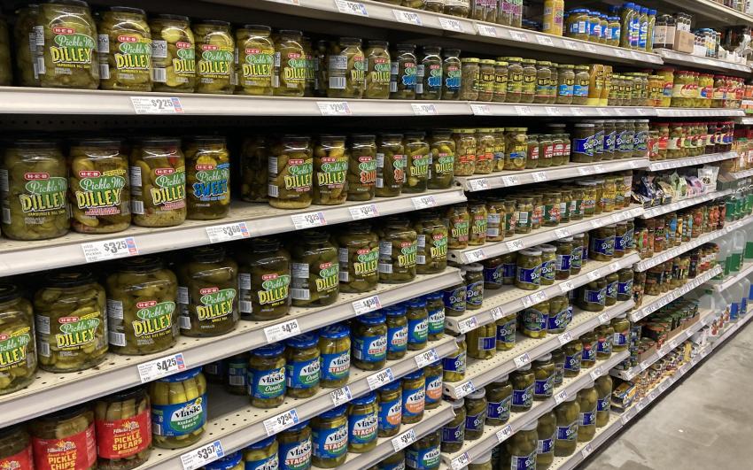 A supermarket aisle showing eight rows of various sized jars of pickles.