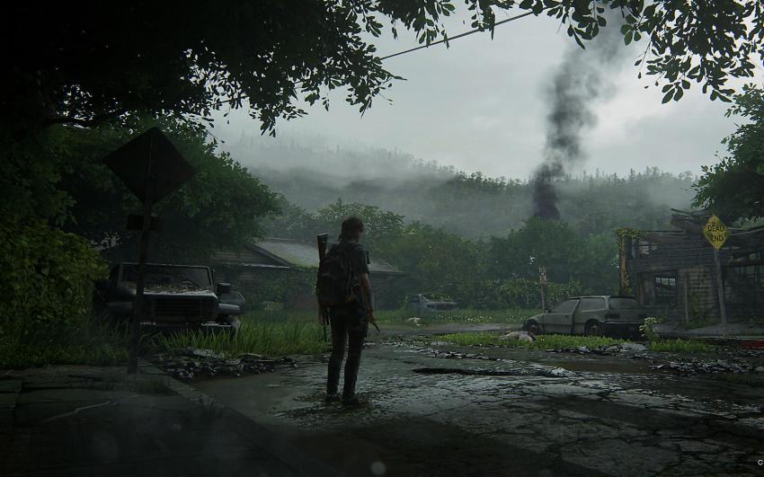 Still from The Last Of Us: A person with a rucksack and a gun faces away from the camera, looking out at a desolate landscape. 