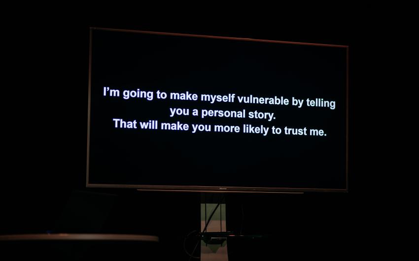 Text projected onto a screen saying “I’m going to make myself vulnerable by telling you a personal story. That will make you more likely to trust me.”