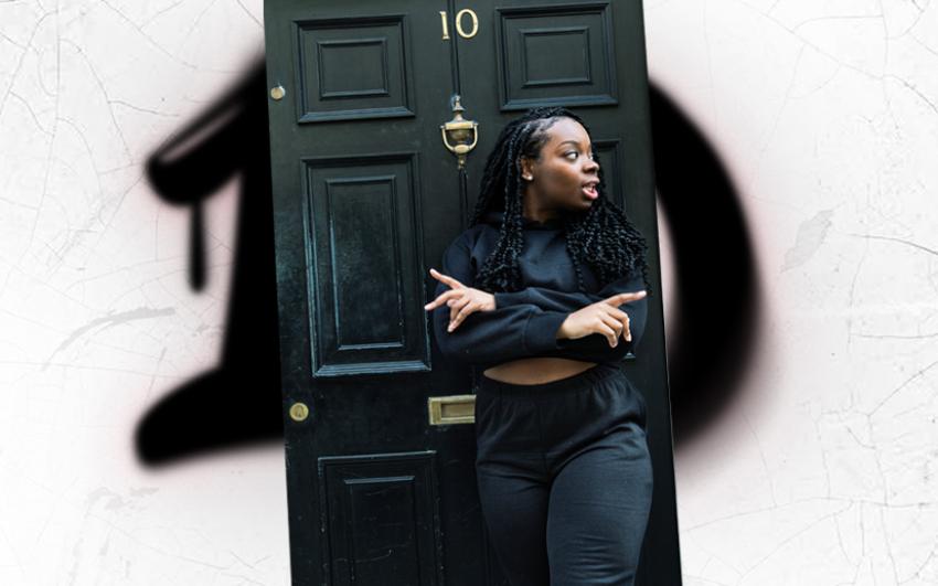 Zakiyyah Deen wearing black sporty clothes, leaning with arms crossed against the door of Number 10 Downing Street.