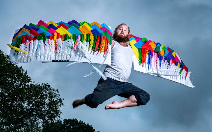 James Rowland leaps in the air, with multicoloured angel wings