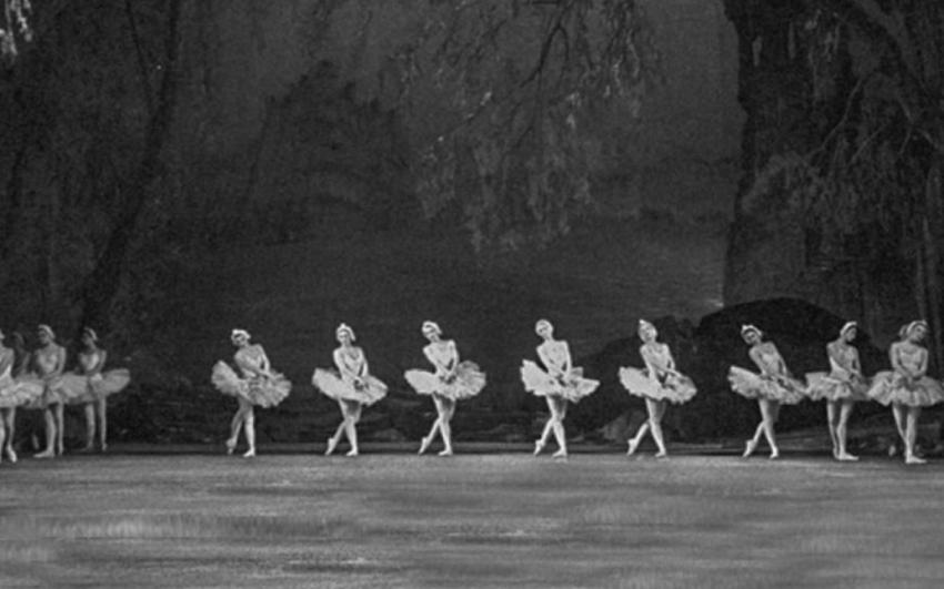 A black and white image of ballerinas in tutus dancing on stage