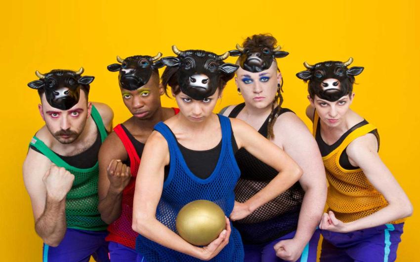 A photo of 5 actors in sports leotards, gym shorts and they are wearing bull masks 